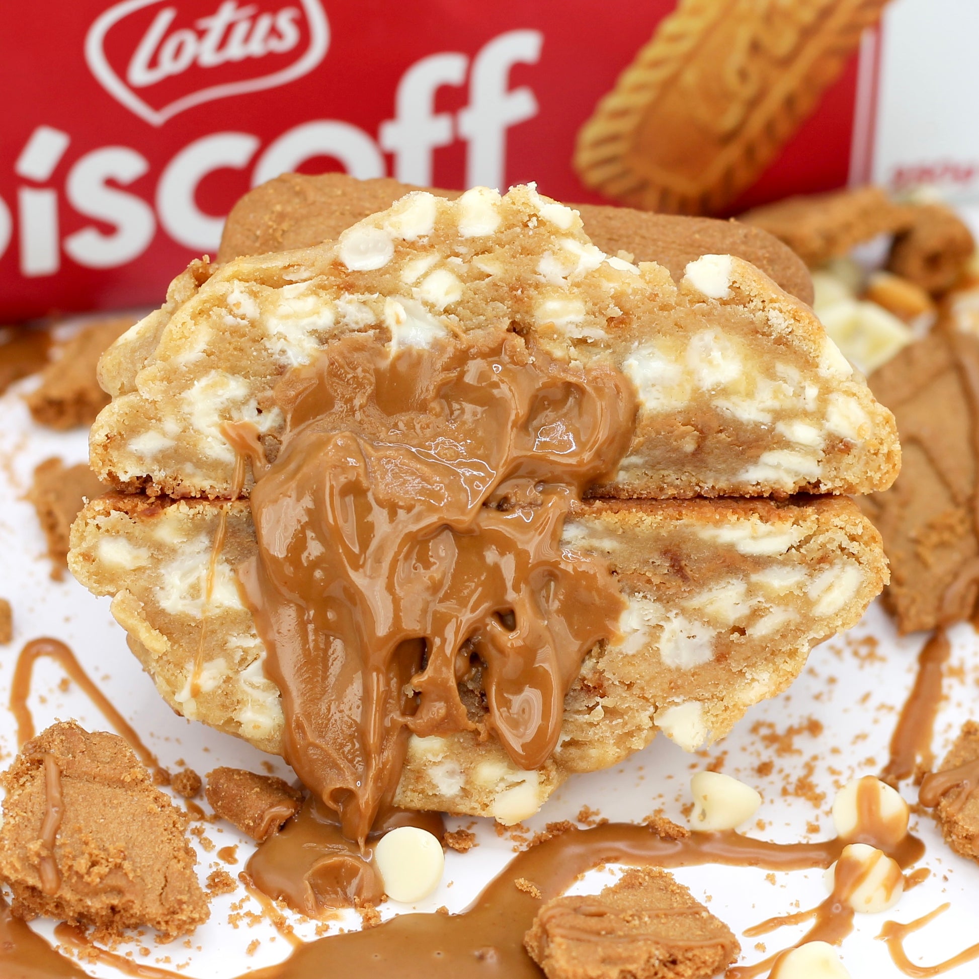 Stuffed Biscoff NYC cookie from Dolly’s Dough, sliced in half to show gooey caramelised spread centre, white chocolate chips, and biscuit chunks. Delivered across the UK