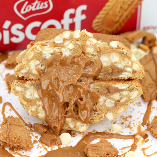 Stuffed Biscoff NYC cookie from Dolly’s Dough, sliced in half to show gooey caramelised spread centre, white chocolate chips, and biscuit chunks. Delivered across the UK